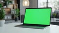 Laptop with green screen, chroma key mock up is on the table. Computer display close-up. Business mockup empty blank