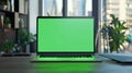Laptop with green screen placed on a workstation, offering clear copy space for creative design or text Royalty Free Stock Photo