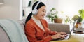 Laptop, headphones and asian woman on couch with work from home opportunity in online or website copywriting. Remote Royalty Free Stock Photo
