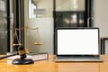 Laptop and judge`s hammer and scales ah justice with notebook on lawyer`s desk in legal concept office