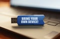 On the laptop keyboard is a flash drive with the inscription - BRING YOUR OWN DEVICE