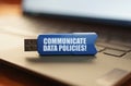 On the laptop keyboard is a flash drive with the inscription - COMMUNICATE DATA POLICIES