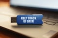 On the laptop keyboard is a flash drive with the inscription - KEEP TRACK OF DATA