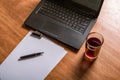 Laptop keyboard, white paper, ink pen and a glass of juice on a wooden table. Blank space for your copy text Royalty Free Stock Photo