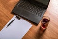 Laptop keyboard, white paper, ink pen and a glass of juice on a wooden table. Blank space for your copy text Royalty Free Stock Photo