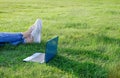 Laptop and legs on green grass. Freelance concept, work or study outdoors. Copy space Royalty Free Stock Photo