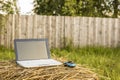 Laptop lies on a haystack on the background wooden fence Royalty Free Stock Photo