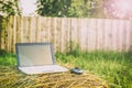 Laptop lies on a haystack on the background wooden fence Royalty Free Stock Photo