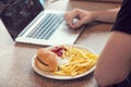 Laptop with lunch, hamburger and french chips