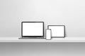 Laptop, mobile phone and digital tablet pc on white concrete wall shelf. Horizontal background Royalty Free Stock Photo