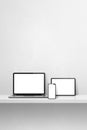 Laptop, mobile phone and digital tablet pc on white concrete wall shelf. Vertical background Royalty Free Stock Photo