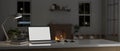 Laptop mockup with accessories on a tabletop in a cozy living room with fireplace at night Royalty Free Stock Photo