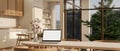 A laptop mockup on a dining table in a beautiful Scandinavian kitchen in a modern spacious home Royalty Free Stock Photo