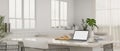 A laptop mockup on a white marble dining table in modern white living room Royalty Free Stock Photo