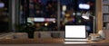 A laptop mockup on a wooden desk in a contemporary home office at night illuminated by dim lights Royalty Free Stock Photo