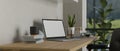 A laptop mockup on a wooden table against the white wall in a modern office room Royalty Free Stock Photo