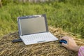 Laptop with modem lies on a haystack near a woman hold her hand Royalty Free Stock Photo