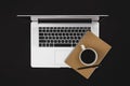 Laptop, notepad and a cup of coffee on a black background isolated, top view. Royalty Free Stock Photo