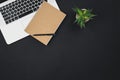Laptop, notepad and a office plant on a black background isolated, top view. Royalty Free Stock Photo