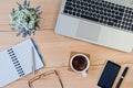 Laptop, notepad with pen, cup of coffee, smartphone, glasses and a bouquet of wildflowers on the desktop. Business concept