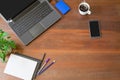 Laptop with office supplies, green plant and hot black coffee with smoke on vintage grunge wooden desk background view from above