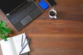 Laptop with office supplies, green plant and hot black coffee with smoke on vintage grunge wooden desk background