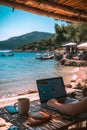 Laptop open on a beachfront table, blending work and leisure with a beautiful coastal backdrop.