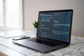 Laptop open displaying coding software on screen, modern workspace with smartphone Royalty Free Stock Photo