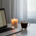Laptop with open documents on a white desk, beside a lit candle labeled \