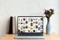 laptop with pinterest website on screen books and flowers in vase