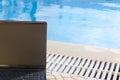 Laptop by the pool, work on holiday concept Royalty Free Stock Photo