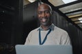 Laptop, portrait and IT black man in server room for research, engineer working in dark data center lobby. Face