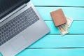 Laptop and a purse with money on a turquoise wooden table. The concept of online work on the Internet, freelancing. Royalty Free Stock Photo