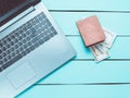 Laptop and a purse with money on a turquoise wooden table. The concept of online work on the Internet, freelancing. Top view. Royalty Free Stock Photo