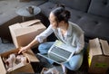 Laptop, real estate and woman moving into new home while unboxing boxes with shoes. Relocation property, computer and Royalty Free Stock Photo