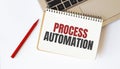 Laptop, red pen and notepad with text PROCESS AUTOMATION in the white background Royalty Free Stock Photo
