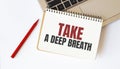 Laptop, red pen and notepad with text TAKE A DEEP BREATH in the white background Royalty Free Stock Photo