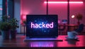 Laptop screen displays word HACKED in neon light, indicating data breach cybersecurity failure. Modern office workplace tech Royalty Free Stock Photo
