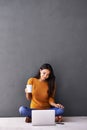 Laptop, search and woman on floor with coffee while streaming, reading or watching movie on wall background. Computer