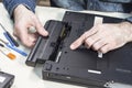 Laptop service. Removal of the battery by a service technician. Tools lie on the table next to