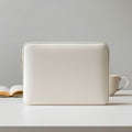 A laptop sleeve on a white surface with a book and a mug in the background in a studio setting Royalty Free Stock Photo