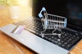 Laptop, small shopping trolley or cart and credit card on wooden table. Internet shopping concept Royalty Free Stock Photo