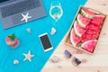 Laptop, smart phone, starfishes, seashells, white wine, watermelon, watermelon lemonade and sunglasses on towel on wooden surface