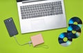 Laptop, smartphone, power bank, CD drives, on a green background. Digital media, gadgets