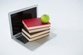 Laptop, stack of books and apple on white background