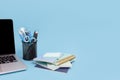 Laptop, stack of notepads, stand with stationery. Student workspace concept Royalty Free Stock Photo