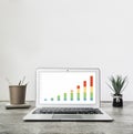 Laptop with statistics chart on screen, flower and office supplies. Copy space. Royalty Free Stock Photo