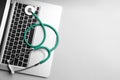 Laptop and stethoscope on light grey table, space for text. Concept of technical support Royalty Free Stock Photo