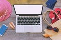 Laptop and summer vacation items on wooden background. View from above