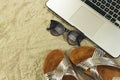 laptop, sunglasses and summer slippers on sand, summer concept.